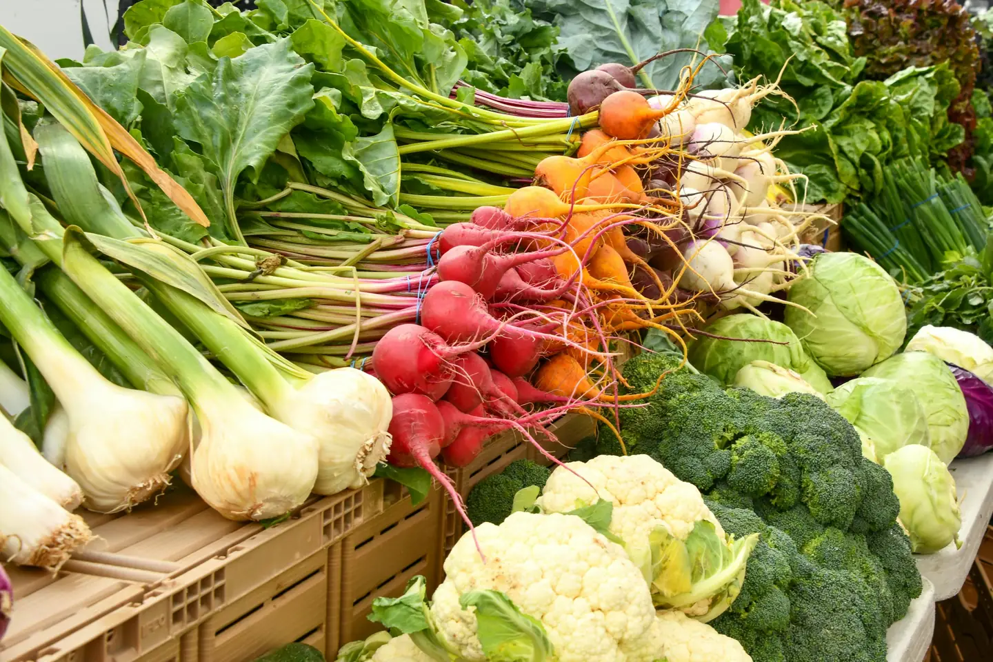 Farm stall piled with bunches of beetroot, spring onions, cauliflower, broccoli and cabbage straight from the field