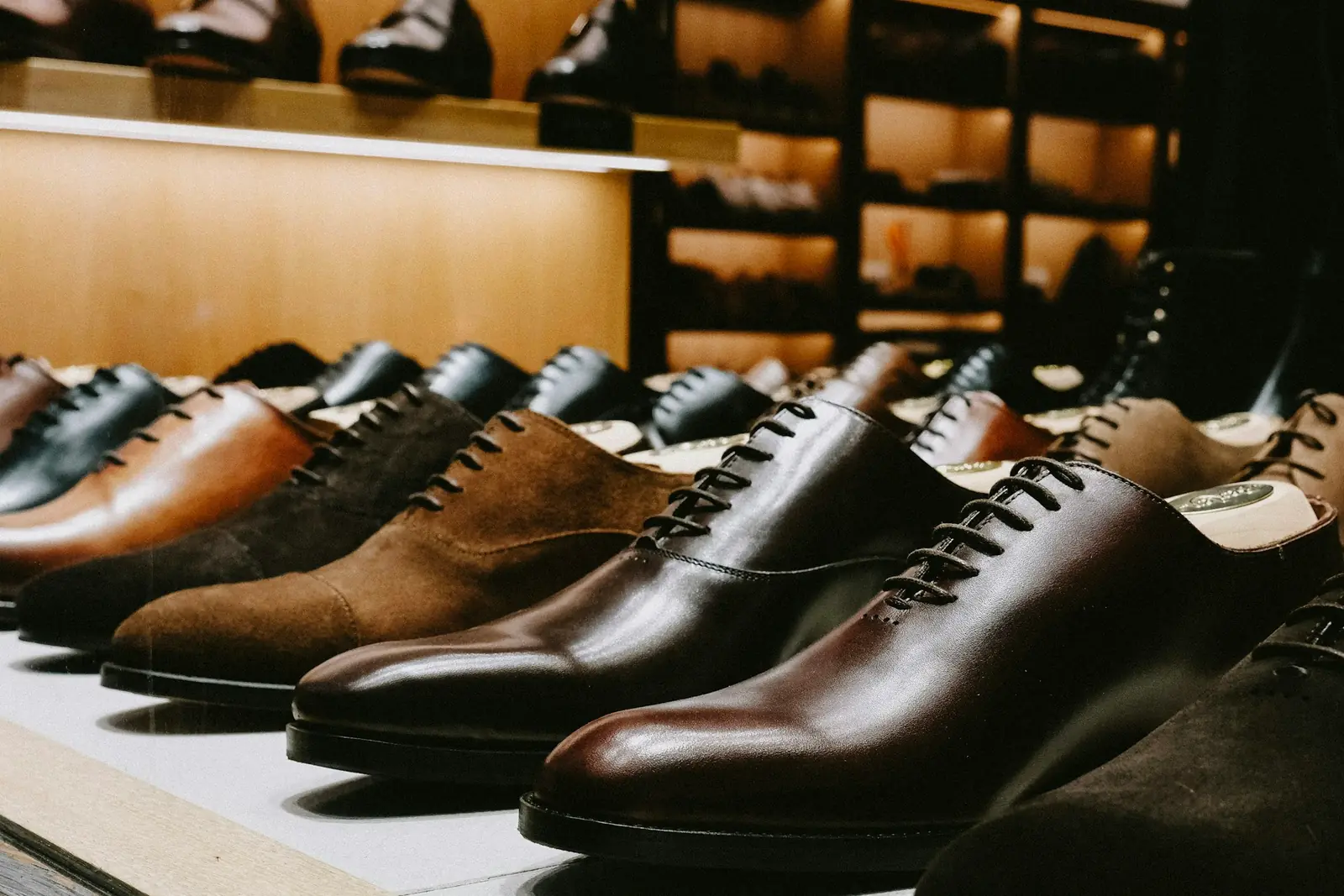 Row of polished leather and suede lace-up shoes on a lit display shelf in a footwear store