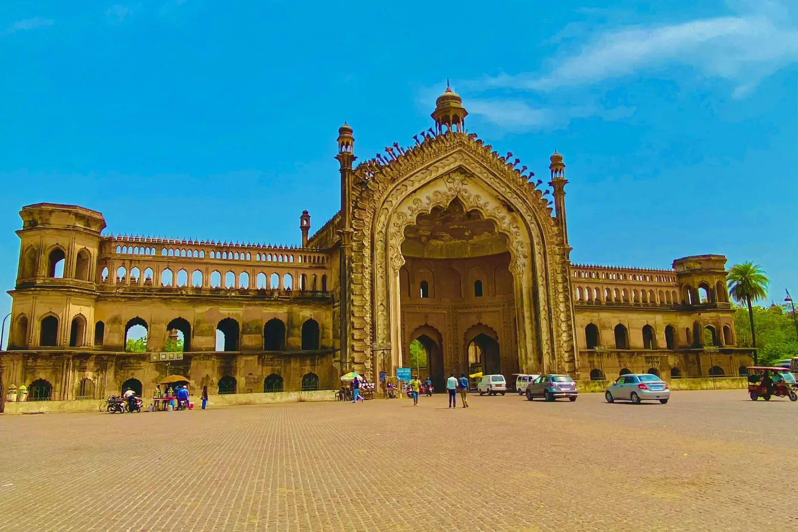 Rumi Darwaza, the ornate 18th-century Awadhi gateway in Lucknow, rising over a wide paved square under a blue sky