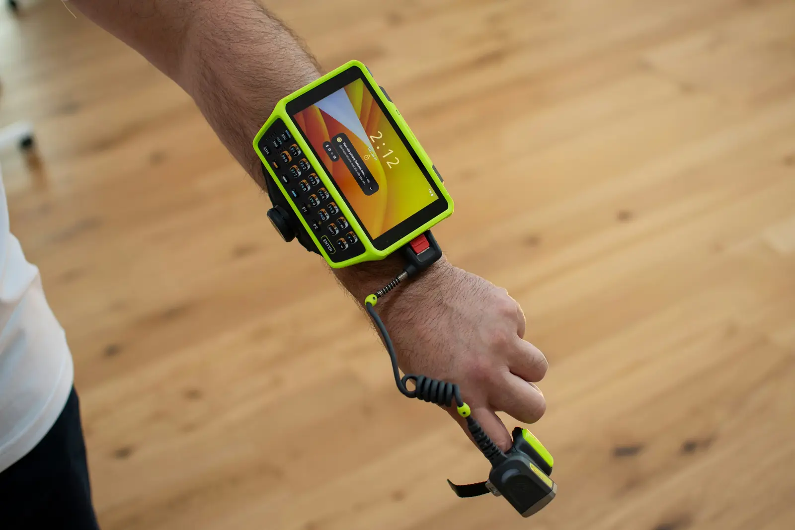 Wrist-mounted rugged mobile computer with a keypad, wired to a finger-worn ring barcode scanner on a worker's arm