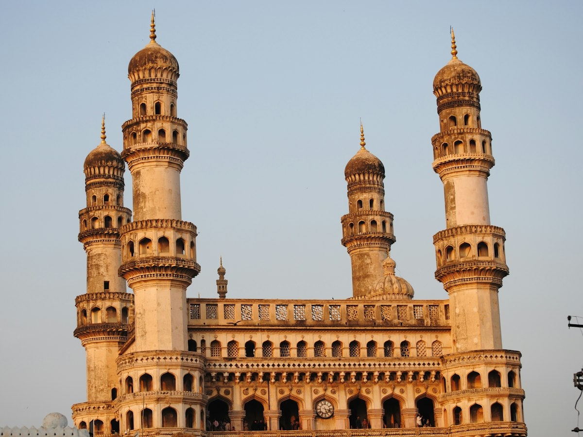 Minarets of the Charminar monument in Hyderabad's old city glowing in warm golden-hour light